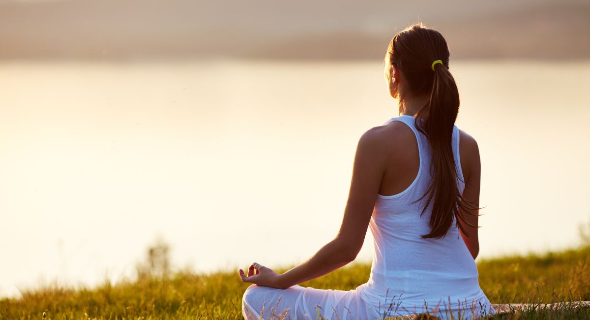 ways to deal with stress woman meditating by water