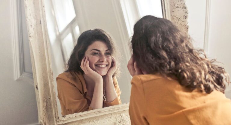 how to stop comparing yourself to others, woman smiling in a mirror