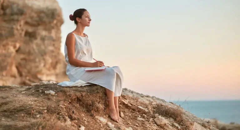 benefits of journaling woman sitting on rocks writing