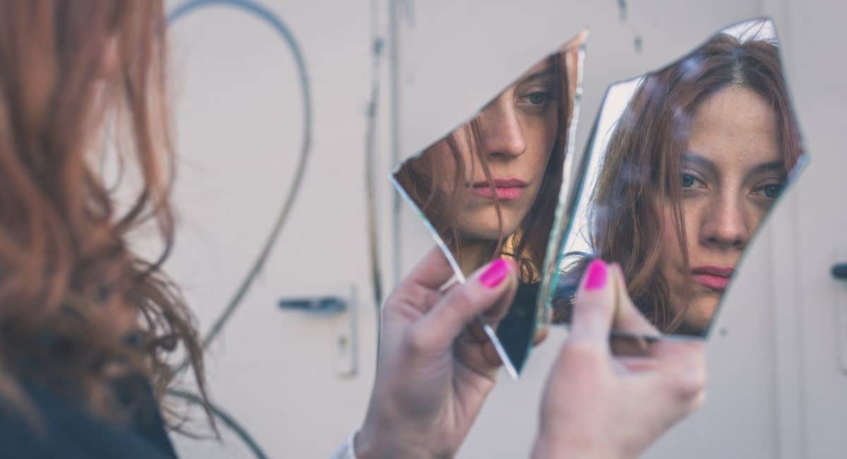 healing from trauma, sad woman looking in broken mirror